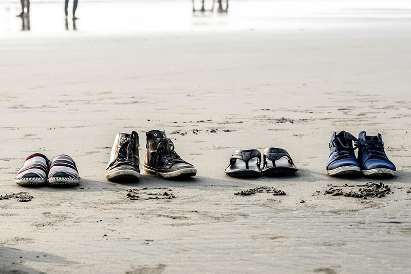 Quatre paires de chaussures au bord d’une plage